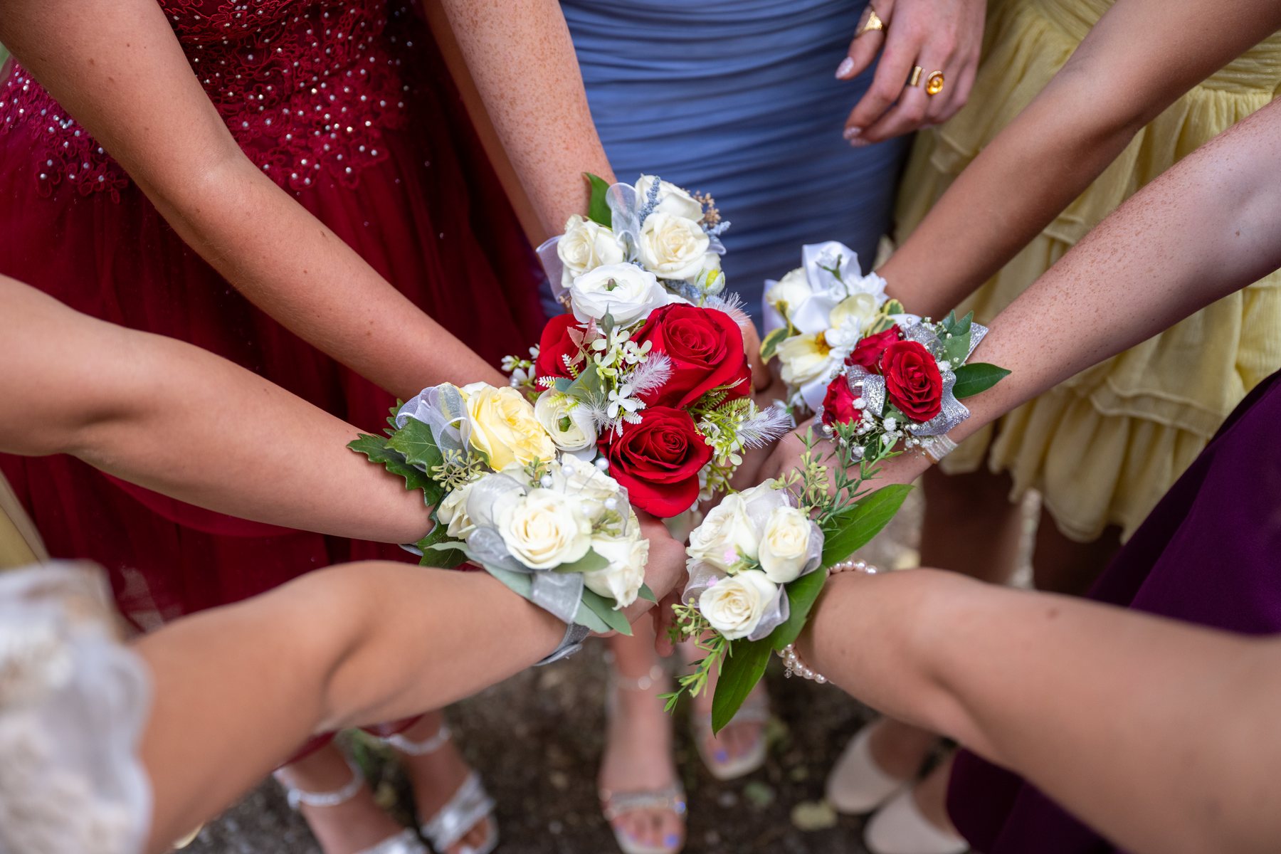 Five wrist corsages in red, white, and yellow, held together in a circle
